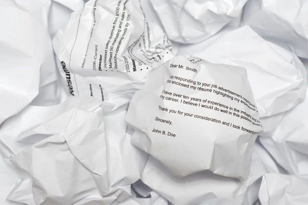 A pile of crumpled papers with visible text resembling a job application letter.